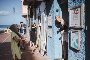 拉斯帕爾馬斯的住宿－La Ventana Azul Surf Hostel，一群人站在一座有冲浪板的建筑外