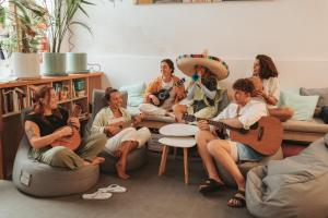 um grupo de mulheres sentadas numa sala de estar a tocar guitarra em La Ventana Azul Surf Hostel em Las Palmas de Gran Canárias