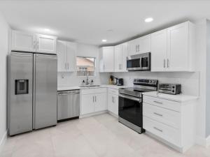 a kitchen with white cabinets and stainless steel appliances at New Villa, Pool, Near Hard Rock 4BR3 in Davie