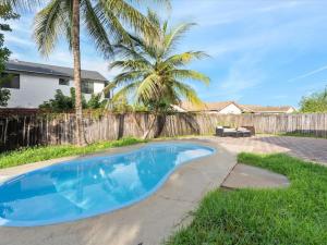 a swimming pool in a yard with a fence and a palm tree at New Villa, Pool, Near Hard Rock 4BR3 in Davie