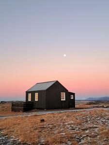 a barn in the middle of a field at sunset at Gíslaholt in Borgarnes