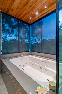 uma grande banheira num quarto com janelas grandes em Refúgio de Altitude em Urupema