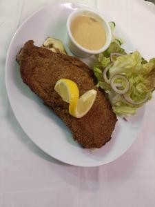 a plate with fish and a salad and a dipping sauce at Hotel Beysang in Châtenois