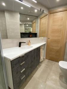 y baño con lavabo, aseo y espejo. en Acogedor apartamento con acabados primera calidad, en Zaragoza