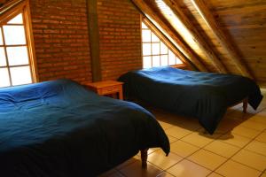 two beds in a room with two windows at Cabaña Familiar en el Bosque Parque La Pirámide 