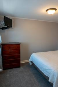a bedroom with a bed and a dresser and a tv at Beach Walk Hotel in Ocean City