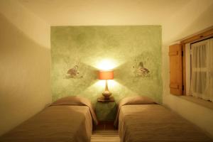 two beds in a room with a lamp on the wall at Monte Do Areeiro in Coruche