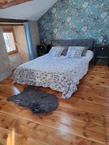a bedroom with a bed and a rug on a wooden floor at Le Grenier des Moineaux in Odeillo-Via