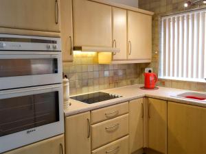a kitchen with wooden cabinets and a stove top oven at Scarborough Rose Apartment in Scarborough