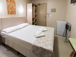 a bedroom with a bed with a table and a refrigerator at Hotel Pitol in Balneário Camboriú