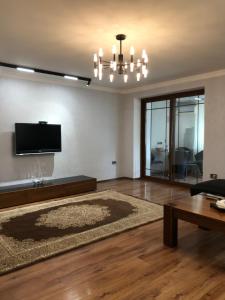a living room with a couch and a tv on a wall at Stylish apartments in the heart of the city! in Tashkent