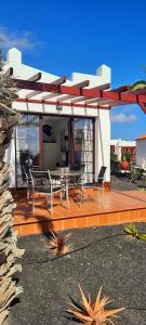 a house with a deck with a table and chairs at Sun beach Caleta 24 in Caleta De Fuste