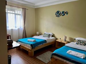 a bedroom with two beds and a window at Masai Heritage Guesthouse in Ololaimutiek