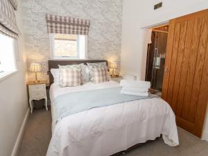 Un dormitorio con una gran cama blanca y una ventana en The Stables and West Wing en York