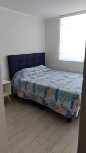 ein Schlafzimmer mit einem Bett mit einer bunten Decke und einem Fenster in der Unterkunft Vista Pacifico, Serena in La Serena