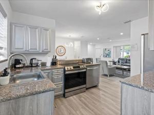 a kitchen with stainless steel appliances and a living room at Modern 3BR2 HEATED POOL GRILL Big BACKYARD in Hollywood