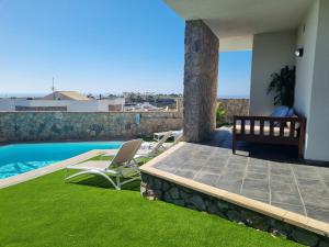 a patio with two chairs and a swimming pool at Villa The Views in Puerto Rico de Gran Canaria