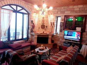 a living room with couches and a tv and a fireplace at Balcony on Trichonida Lake in Kríon Nerón