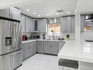 cocina con armarios blancos y nevera de acero inoxidable en Modern 4BR2 HEATED POOL GRILL Big backyard en Miami Gardens