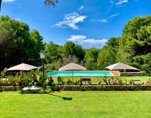 una piscina con sombrillas y sillas en un parque en Villa Scinata Dimora Storica, en Nardò