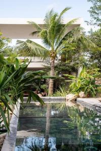 a swimming pool with a palm tree next to a house at Villa 16Tulum in Tulum