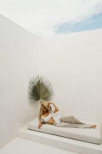 a woman sitting on a white shelf with a plant at Villa 16Tulum in Tulum