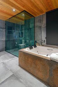 een badkamer met een bad en een glazen douche bij Refúgio de Altitude in Urupema