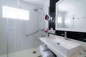 a white bathroom with a sink and a shower at Lani's Suites de Luxe - Adults Only in Puerto del Carmen