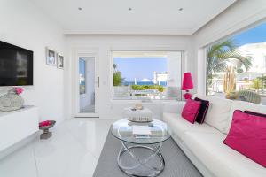 Sala de estar blanca con sofá blanco y almohadas rosas en Lani's Suites de Luxe - Adults Only en Puerto del Carmen