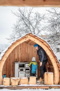 un homme et un enfant debout à l'intérieur d'un igloo en bois dans l'établissement Töllhof Apartments and Farm, à Naz-Sciaves