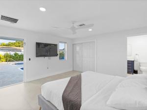 um quarto branco com uma cama e uma televisão na parede em New 4 Bedroom Villa W Private Backroom, Pool em Pembroke Pines