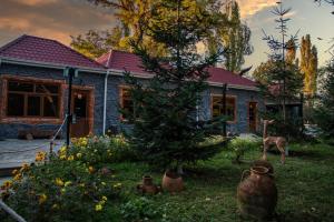 une maison avec un arbre et une girafe dans la cour dans l'établissement Karvan Qusar, à Qusar