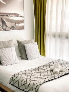 ein Bett mit weißer Bettwäsche und Kissen in einem Schlafzimmer in der Unterkunft Adorable studio sur la plage in Biarritz