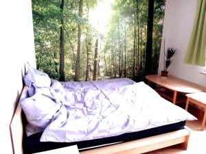 ein Bett in einem Schlafzimmer mit einem Fenster mit Bäumen in der Unterkunft Zentral und doch Natur in Köln