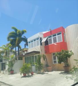 ein rotes Gebäude mit Palmen davor in der Unterkunft Cozy Beach Apartment in San Juan