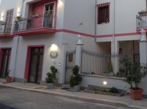 a white and red building with plants in front of it at B&B Le Ortensie in San Vito lo Capo