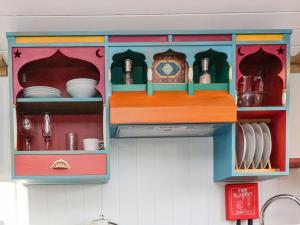a toy kitchen cabinet with dishes and a clock at The Storyteller in York +4 photos