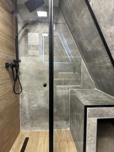 a shower with a glass door next to a staircase at Loon Moon Mountain Chalets in Sarajevo