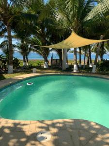 a swimming pool with a tent and palm trees at Cabo tortuga bungalows in Monterrico