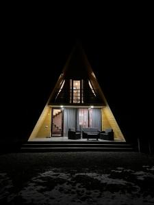 a triangle shaped house with a living room in the dark at LUMA Sadgeri (Borjomi) in Borjomi