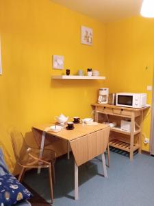 uma cozinha com uma mesa e um micro-ondas numa parede amarela em Studio Mer Centre équestre em Mers-les-Bains