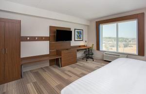 Habitación de hotel con cama y escritorio con TV. en Holiday Inn Express & Suites Covington, an IHG Hotel en Covington
