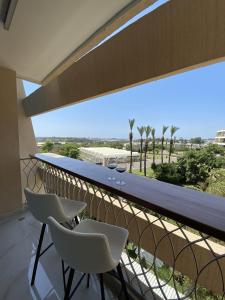 a balcony with two chairs and a table with wine glasses at Rose Suite in Caesarea