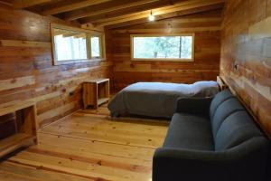 ein Zimmer mit einem Sofa und einem Bett in einer Hütte in der Unterkunft Acogedora Cabaña del Bosque - Parque La Pirámide 