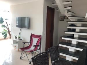a living room with a red chair and a staircase at PRAIA GRANDE LOFT DUPLEX in Arraial do Cabo