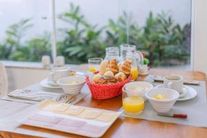 uma mesa com uma cesta de pão e chávenas de sumo de laranja em Pousada CafeMar Búzios em Búzios