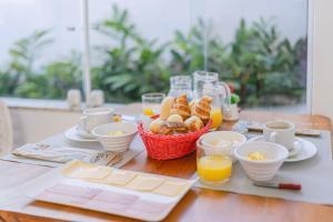 a table with a basket of bread and cups of orange juice at Pousada CafeMar Búzios in Búzios