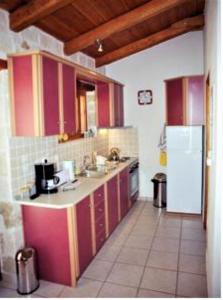 cocina con armarios rojos y nevera blanca en Villa Belvedere - Sea view apts near Banana beach, en Vasilikos