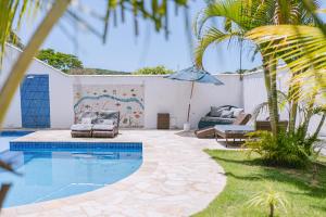 a swimming pool in a yard with a couch and an umbrella at Pousada CafeMar Búzios in Búzios