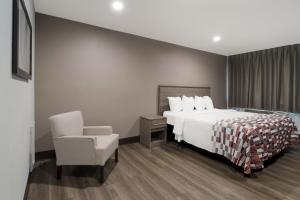 a hotel room with a bed and a chair at Red Roof Inn Rocky Mount - Battleboro in Battleboro +24 photos